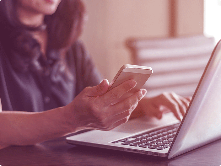 mulher mexendo no notebook e no celular para conferir o seu score pelo serasa