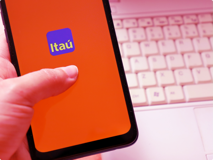 Segurando o celular acessando o aplicativo do itáu para saber mais de como conseguir um cartão itaú personnalité