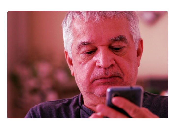 Senhor em sua casa olhando o seu celular e conferindo as novas regras para aposentadoria do INSS em 2022
